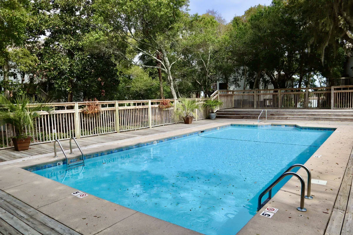 This image features a tranquil, sparkling swimming pool surrounded by lush greenery and a comfortable deck area. The scene suggests opportunities for swimming, sunbathing, and social gatherings, perfectly representing the seasonal saltwater pool described in the section.